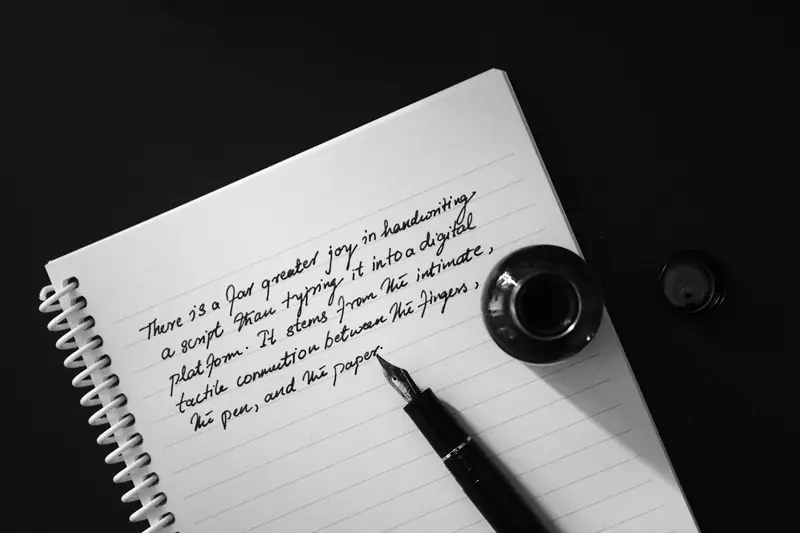 A fountain pen and inkwell resting on a notebook